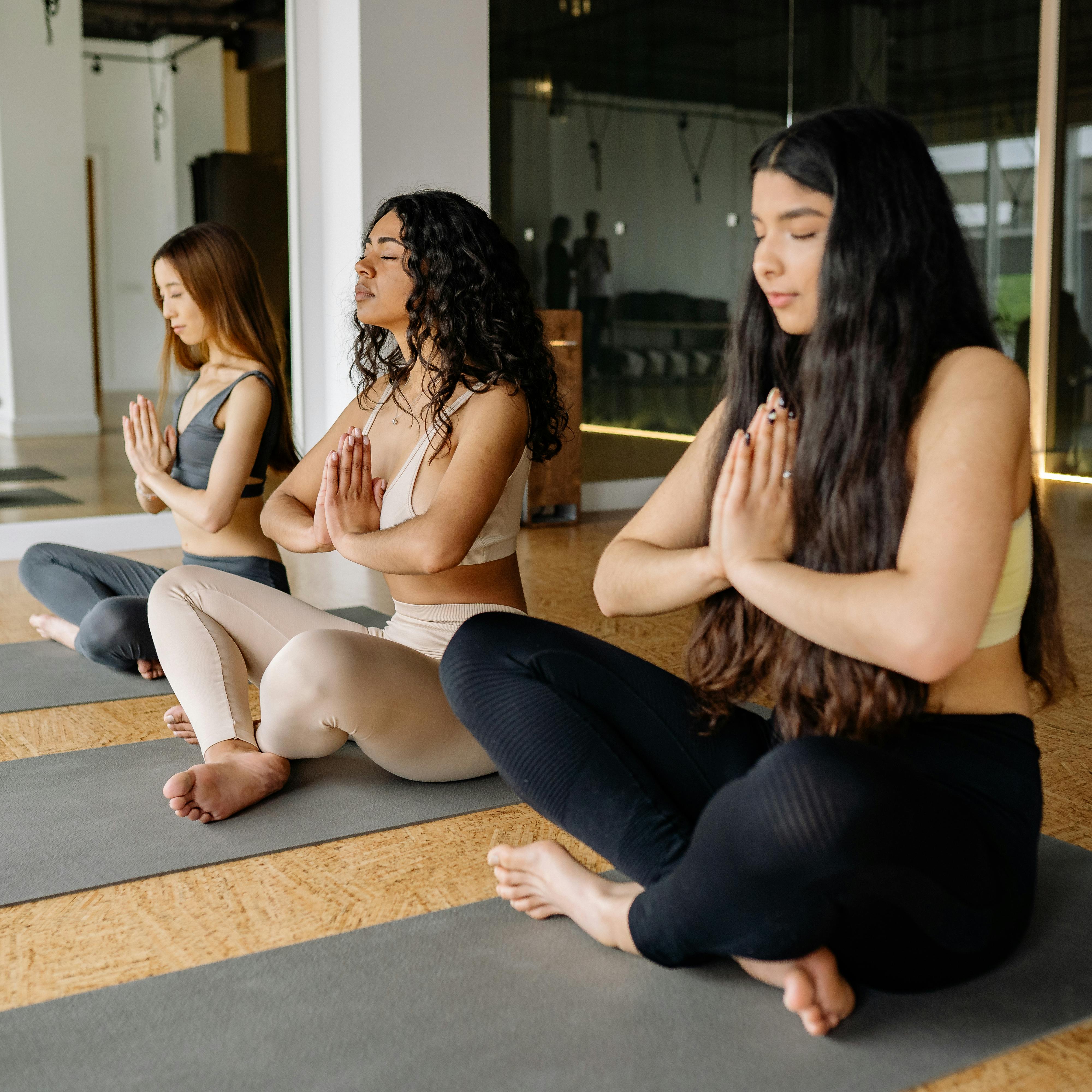 Three women meditating in a yoga class, fostering concentration and well-being.